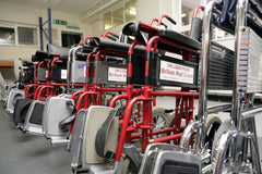 A photograph of several red attendant-propelled wheelchairs. The wheelchairs have the text 